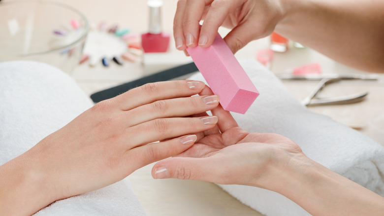 woman using pink nail buffer