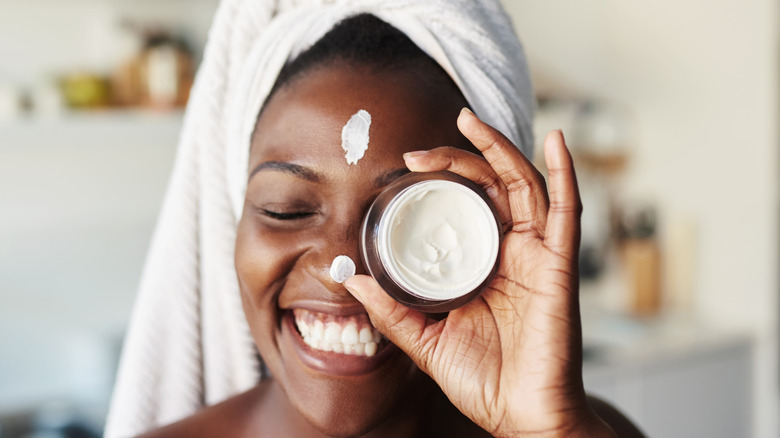 smiling woman with moisturizer jar