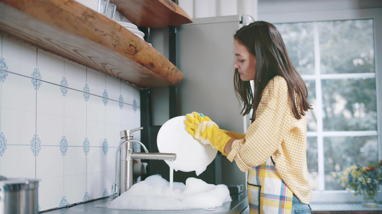 woman washing dishes wearing gloves