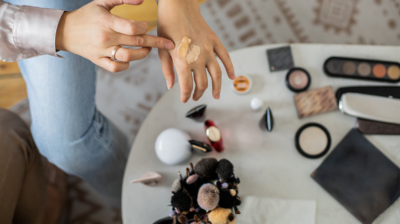 Woman mixing makeup on hand 