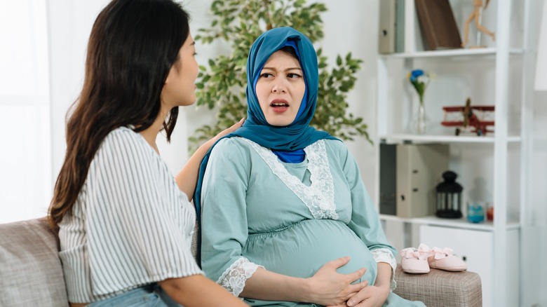 upset pregnant woman talking to friend