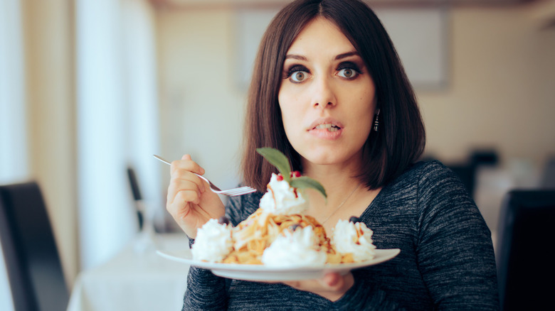 Scared pregnant woman eating cake