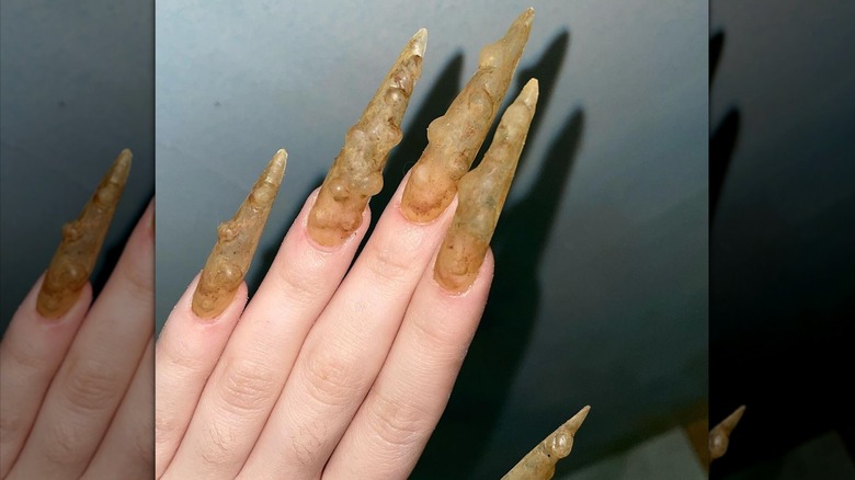 Long yellow stiletto grotesque nails.