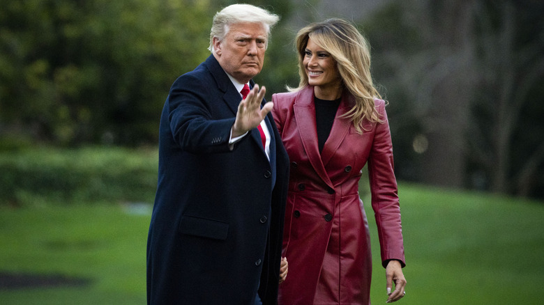 Donald Trump with Melania Trump, wearing a long red leather coat.