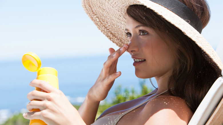Woman applying sunscreen to nose
