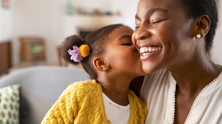 Child giving mom cheek kiss