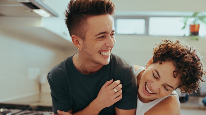 Young queer couple laughing and hugging