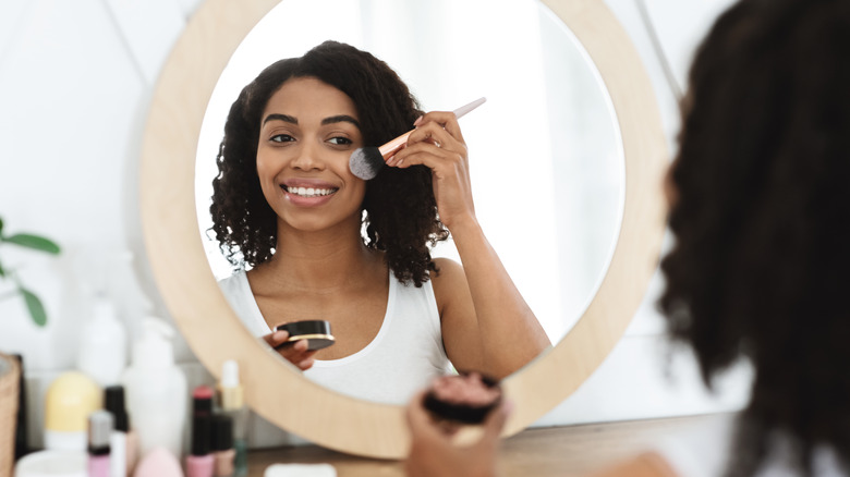 Smiling woman applying blush