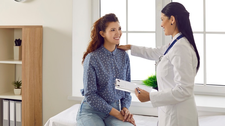 Smiling woman talking to doctor 