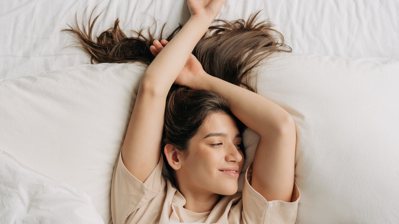 Young woman with long hair across bed pillows
