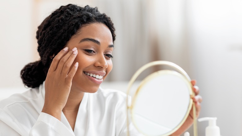 woman looking at face with mirror