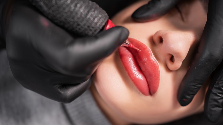 woman getting lip tattoo