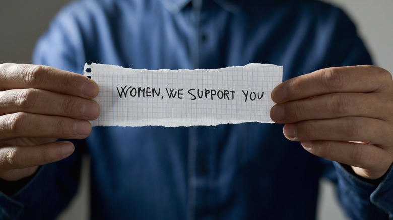 Man holds up written support for women
