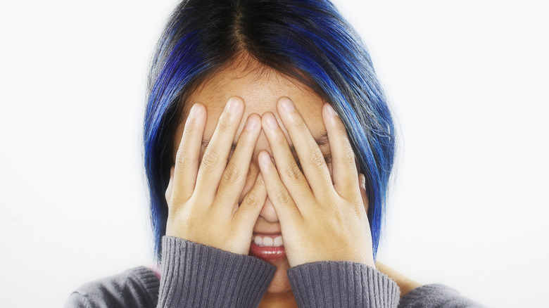 Shy woman with hands covering face