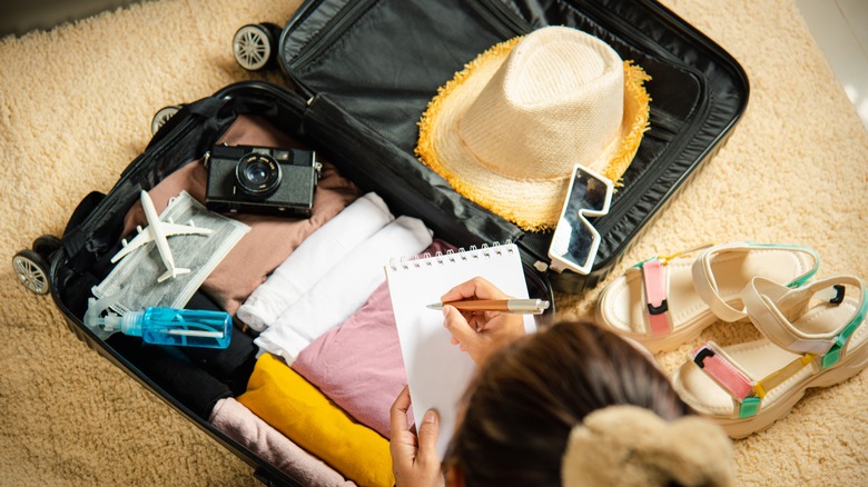 Luggage With Clothing and Woman Writing Notes