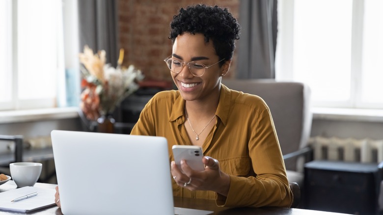 Woman at computer with phone