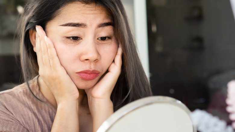 woman checks her eyes in the mirror