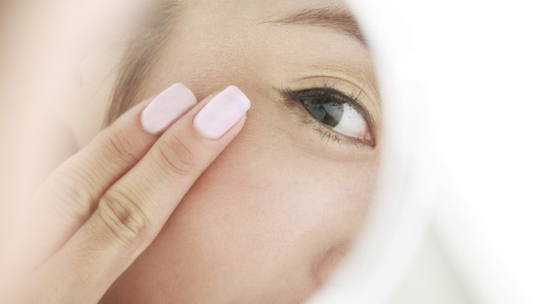 woman looking at her youthful eye in the mirror