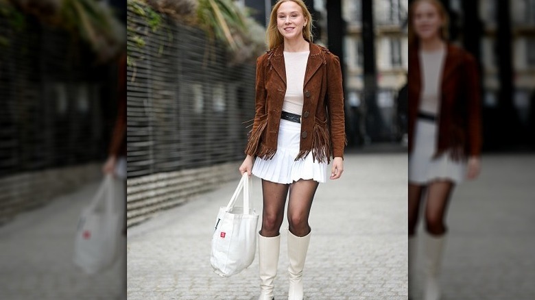 Woman in white outfit with brown suede coat