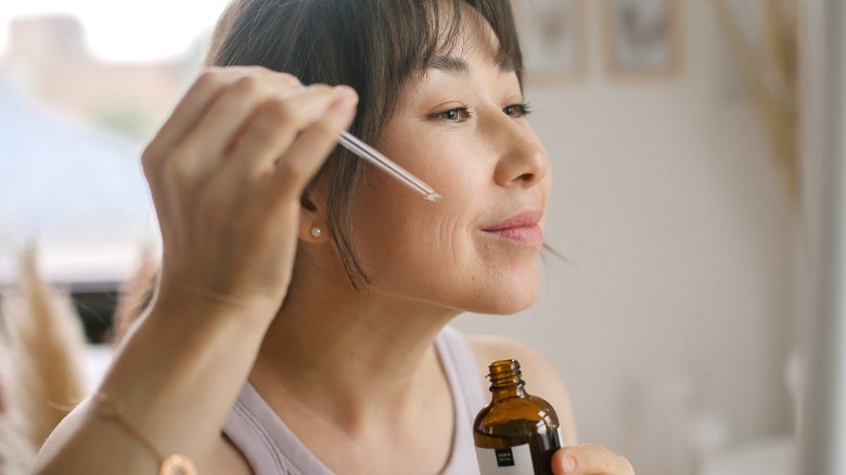 Smiling woman applying face oil