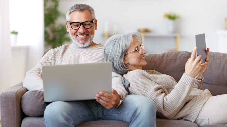 Couple working on their own devices on couch