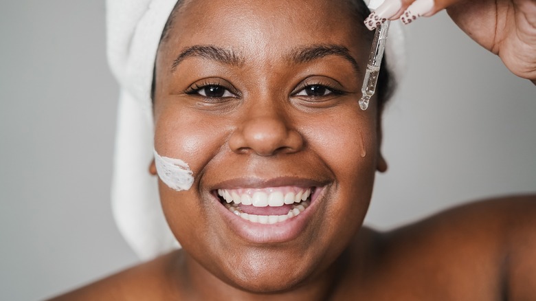 smiling Black woman applying skincare