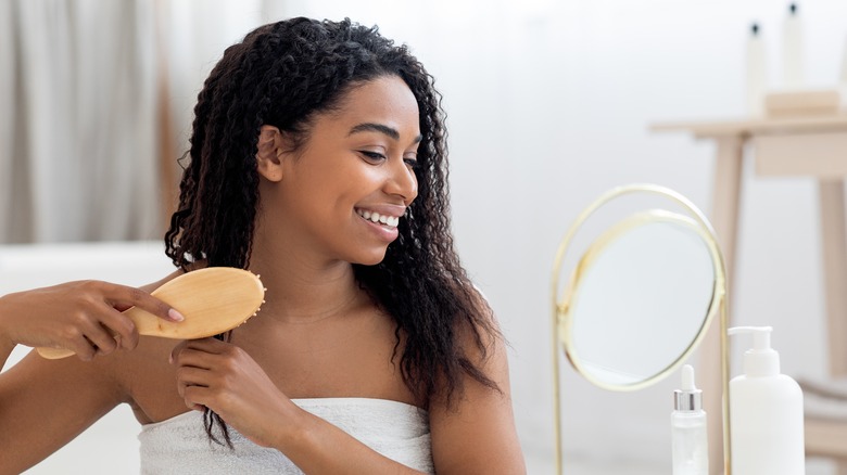 woman brushing through curly hair