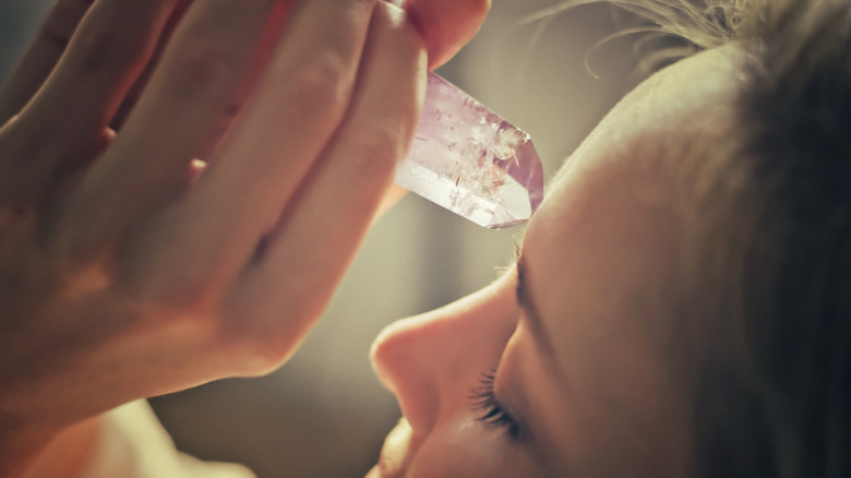 Woman applying rose quartz to forehead 