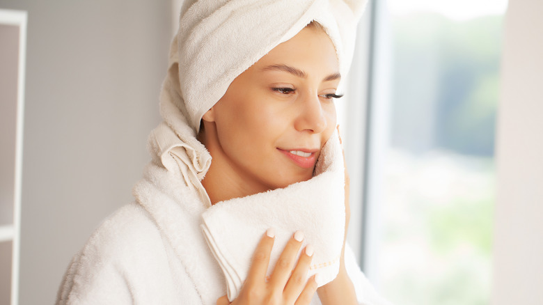 woman holding towel to face