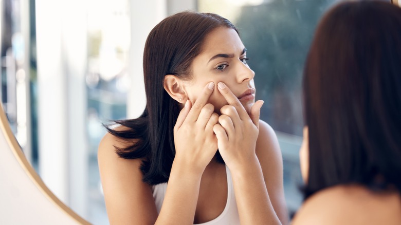 woman squeezing pimple