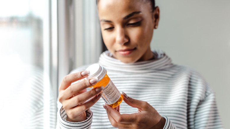 woman looking at prescription bottle