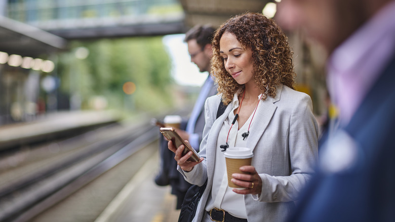 Woman commuting, holding coffee, phone