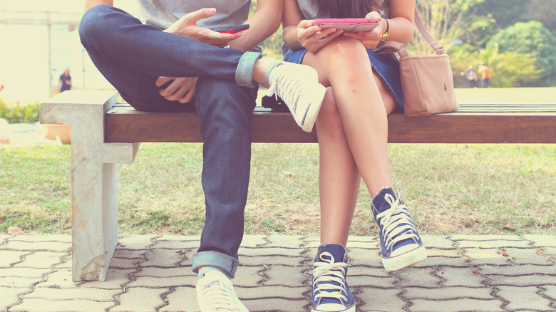 Legs of couple sitting on bench