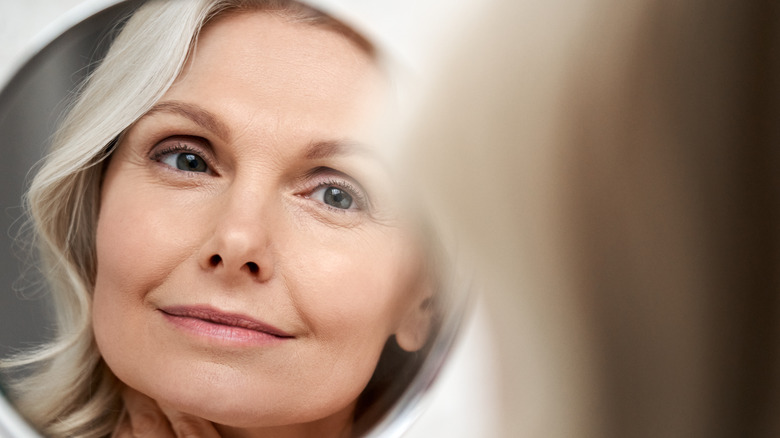 older woman using moisturizer on face