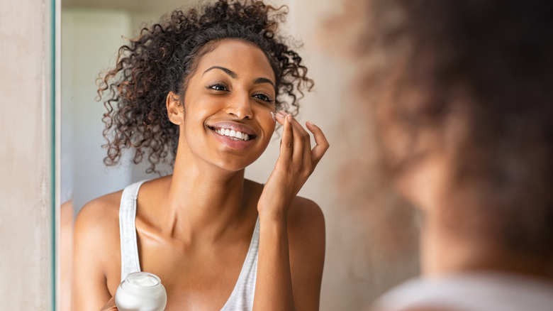 young woman putting glycerin moisturizer on face