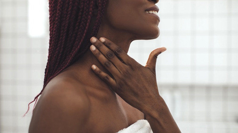 Woman applying lotion to neck