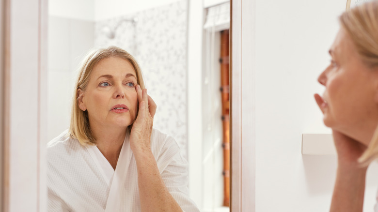 Woman inspecting face in mirror