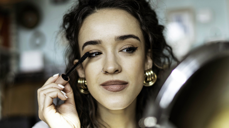 Smiling woman applying mascara