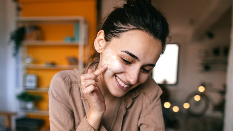 Smiling woman applying cosmetics