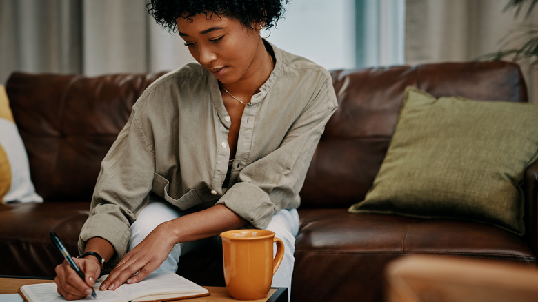 Woman journaling while sitting on couch