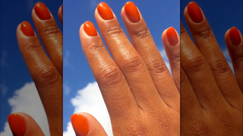 Bright orange nails against sky