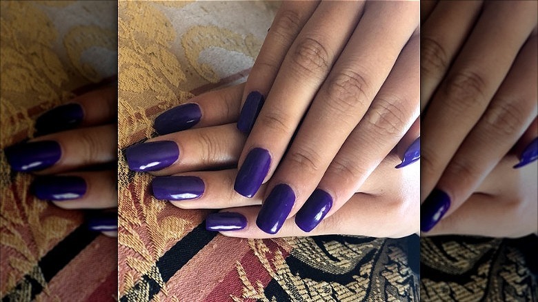 woman's hands dark purple manicure