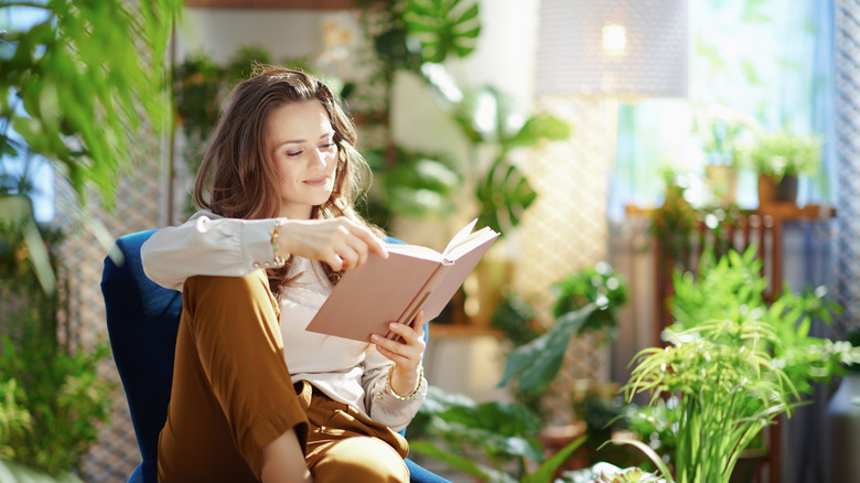 woman reading book surrounded by plants