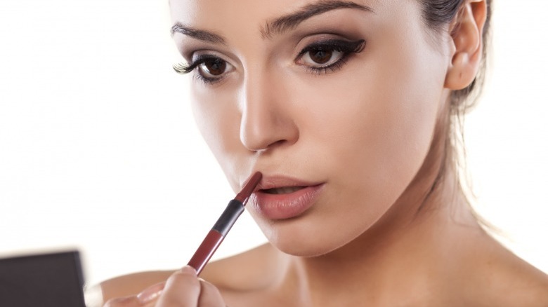 Brunette woman applying lip liner