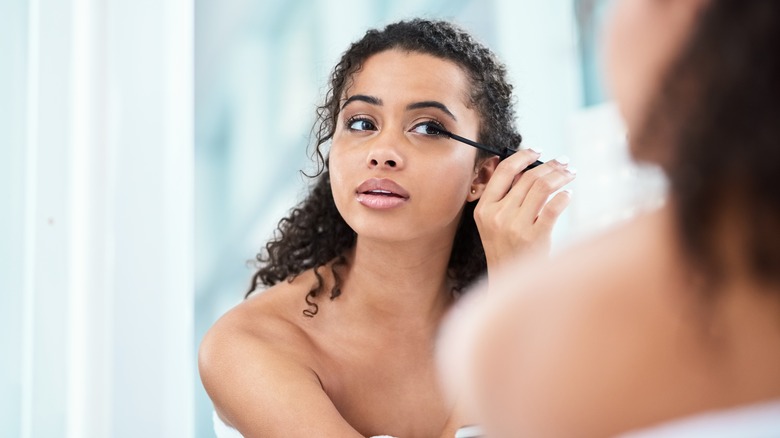 Woman applying mascara in mirror