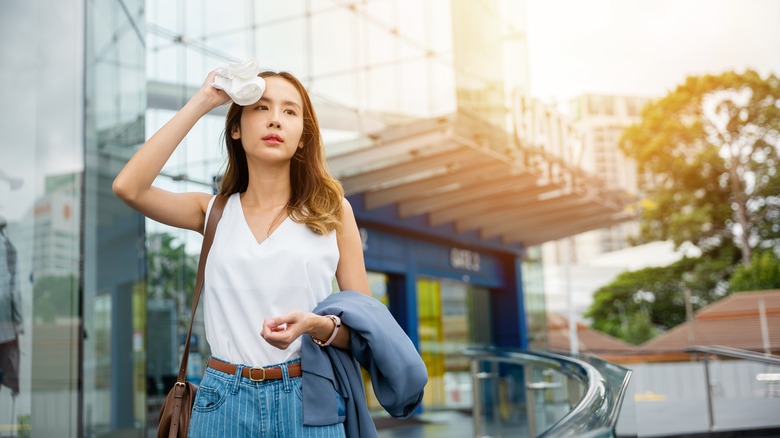 Woman walking outside and dabbing her forehead