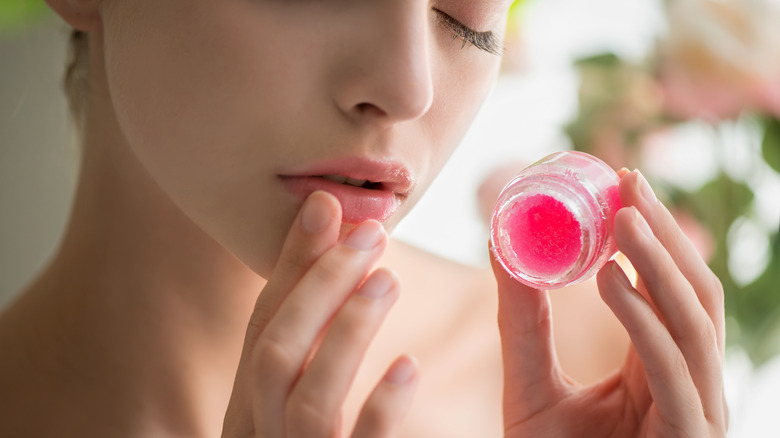 Woman applying scrub to lips