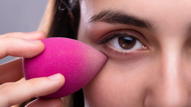 Woman fixing concealer makeup