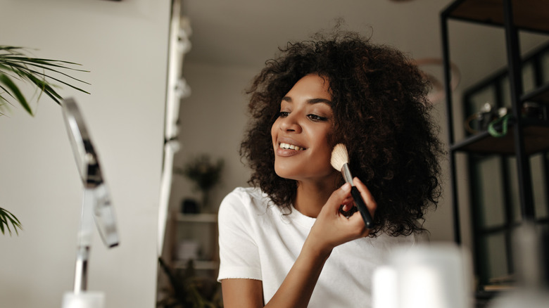 Woman applying makeup in mirror