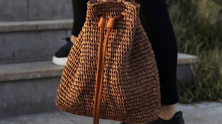 Person holding raffia bucket bag
